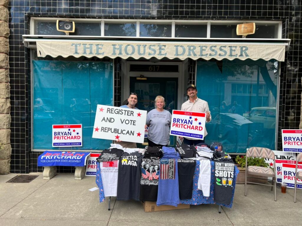 Three men standing in front of a building with political signs.